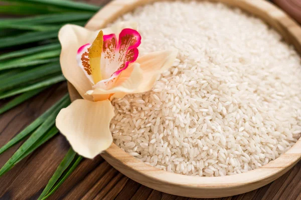 Arroz en plato de madera y anís sobre fondo de madera marrón. Arroz y especias en contenedor ecológico. Listos para cocinar. Set para spa . — Foto de Stock