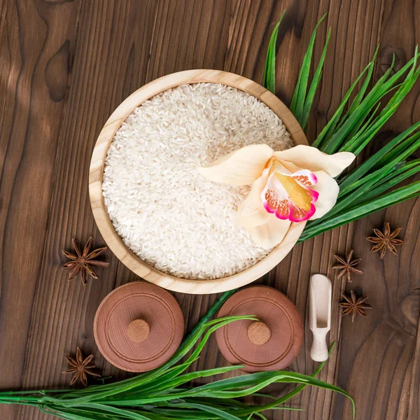 Arroz em placa de madeira e anis sobre fundo de madeira marrom. Arroz e especiarias em recipiente ecológico. Preparado para cozinhar. Conjunto para spa . — Fotografia de Stock