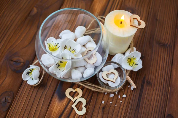Witte stenen in een glazen vaas, bloemen en een grote kaars voor spa- en ontspanningsfaciliteiten — Stockfoto