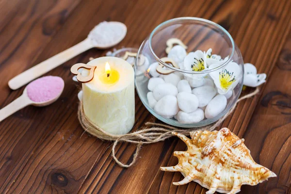 Weiße Steine in einer Glasvase, Blumen und eine große Kerze für Wellness und Entspannung — Stockfoto