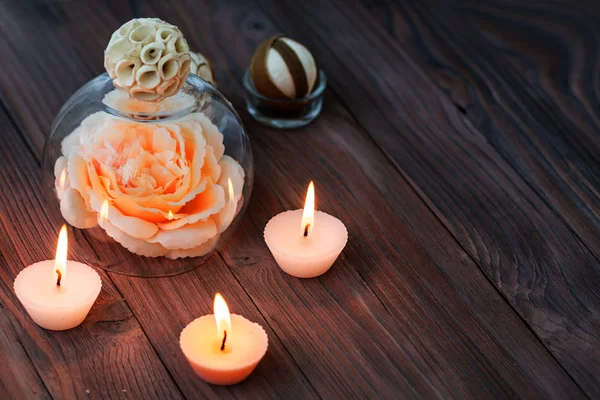 A large pink flower in a glass globe, decorations and various interesting elements on a dark wooden background. Set for spa and relaxation — Stock Photo, Image