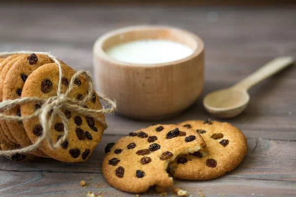 Honey cookies with raisins and milk on wooden table