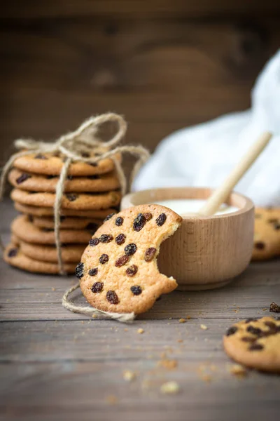 Honey cookies with raisins and milk on wooden table