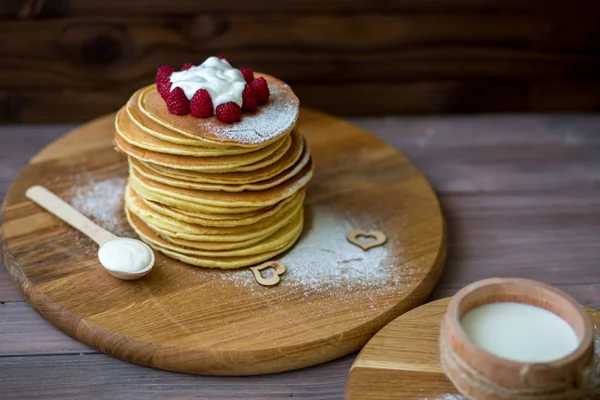 Tasty homemade pancakes with cream and raspberry. On wooden table. — Stock Photo, Image