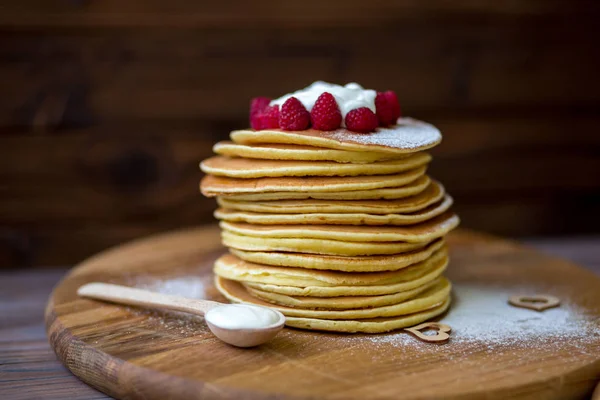 Tasty homemade pancakes with cream and raspberry. On wooden table. — Stock Photo, Image