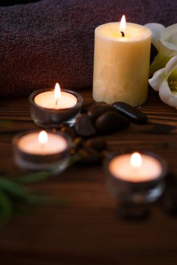 Bir mum bir cam vazo, dekorasyon ve koyu ahşap arka plan üzerinde çeşitli ilginç unsurlar. Yanan mumlar. Spa için ayarla ve masaj.