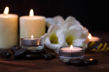 Bir mum bir cam vazo, dekorasyon ve koyu ahşap arka plan üzerinde çeşitli ilginç unsurlar. Yanan mumlar. Spa için ayarla ve masaj.