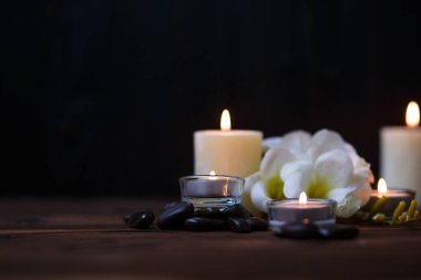 Bir mum bir cam vazo, dekorasyon ve koyu ahşap arka plan üzerinde çeşitli ilginç unsurlar. Yanan mumlar. Spa için ayarla ve masaj.