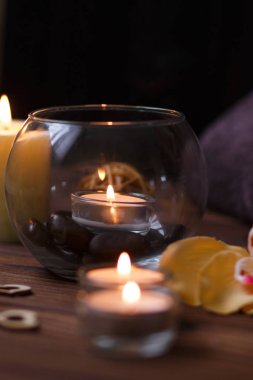 Bir mum bir cam vazo, dekorasyon ve koyu ahşap arka plan üzerinde çeşitli ilginç unsurlar. Yanan mumlar. Spa için ayarla ve masaj.