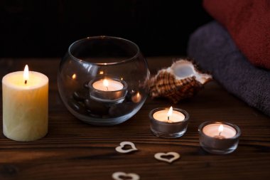 Bir mum bir cam vazo, dekorasyon ve koyu ahşap arka plan üzerinde çeşitli ilginç unsurlar. Yanan mumlar. Spa için ayarla ve masaj.