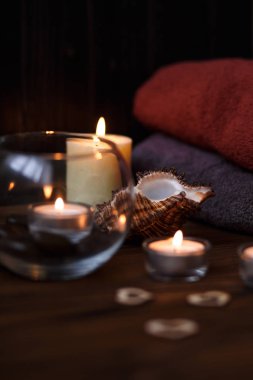 Bir mum bir cam vazo, dekorasyon ve koyu ahşap arka plan üzerinde çeşitli ilginç unsurlar. Yanan mumlar. Spa için ayarla ve masaj.