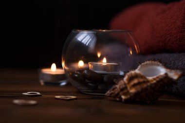 Bir mum bir cam vazo, dekorasyon ve koyu ahşap arka plan üzerinde çeşitli ilginç unsurlar. Yanan mumlar. Spa için ayarla ve masaj.
