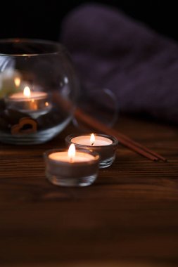 Bir mum bir cam vazo, dekorasyon ve koyu ahşap arka plan üzerinde çeşitli ilginç unsurlar. Yanan mumlar. Spa için ayarla ve masaj.