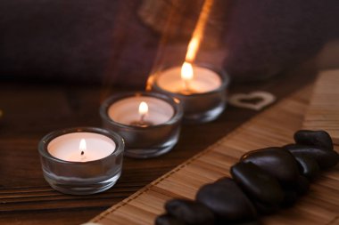 Bir mum bir cam vazo, dekorasyon ve koyu ahşap arka plan üzerinde çeşitli ilginç unsurlar. Yanan mumlar. Spa için ayarla ve masaj.