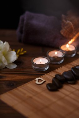 Bir mum bir cam vazo, dekorasyon ve koyu ahşap arka plan üzerinde çeşitli ilginç unsurlar. Yanan mumlar. Spa için ayarla ve masaj.