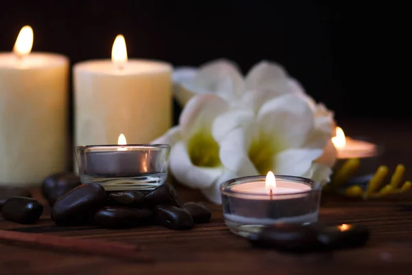 Uma vela em um vaso de vidro, decoração e vários elementos interessantes em um fundo de madeira escuro. Velas a arder. Conjunto para spa e massagem . — Fotografia de Stock