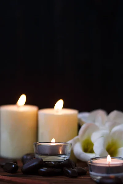 Uma vela em um vaso de vidro, decoração e vários elementos interessantes em um fundo de madeira escuro. Velas a arder. Conjunto para spa e massagem . — Fotografia de Stock