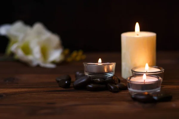 Una vela en un jarrón de vidrio, decoración y varios elementos interesantes sobre un fondo de madera oscura. Velas encendidas. Set para spa y masaje . — Foto de Stock