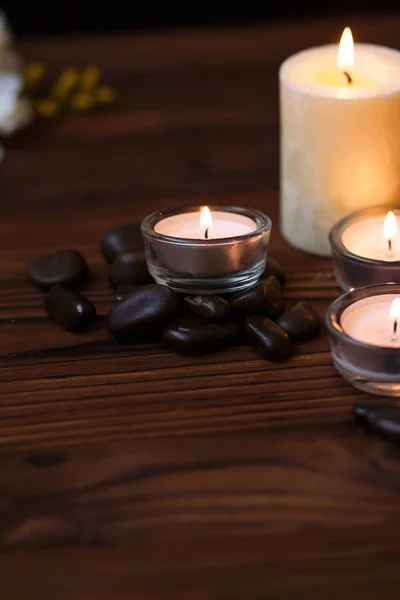 Uma vela em um vaso de vidro, decoração e vários elementos interessantes em um fundo de madeira escuro. Velas a arder. Conjunto para spa e massagem . — Fotografia de Stock