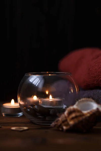 Bir mum bir cam vazo, dekorasyon ve koyu ahşap arka plan üzerinde çeşitli ilginç unsurlar. Yanan mumlar. Spa için ayarla ve masaj.