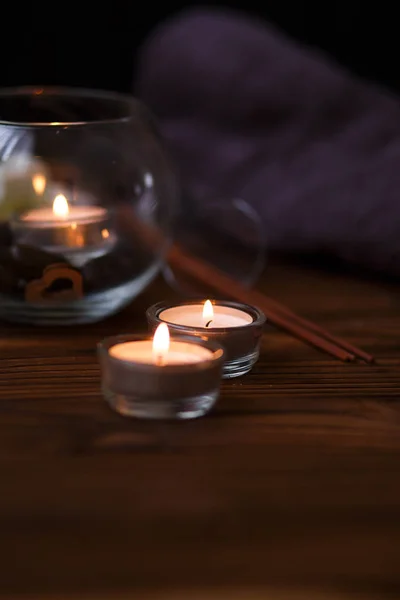 Uma vela em um vaso de vidro, decoração e vários elementos interessantes em um fundo de madeira escuro. Velas a arder. Conjunto para spa e massagem . — Fotografia de Stock