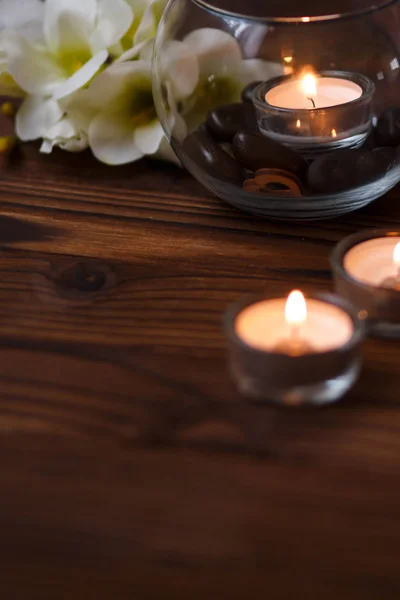 A candle in a glass vase, decoration and various interesting elements on a dark wooden background. Candles burning. Set for spa and massage. — Stock Photo, Image