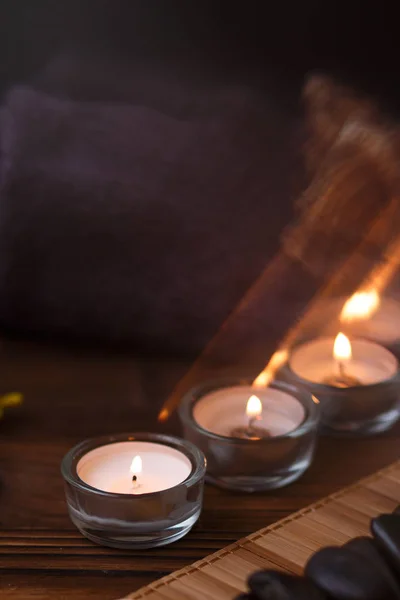 Bir mum bir cam vazo, dekorasyon ve koyu ahşap arka plan üzerinde çeşitli ilginç unsurlar. Yanan mumlar. Spa için ayarla ve masaj.