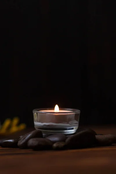 Una candela in un vaso di vetro, decorazione e vari elementi interessanti su uno sfondo di legno scuro. Candele accese. Set per spa e massaggi . — Foto Stock