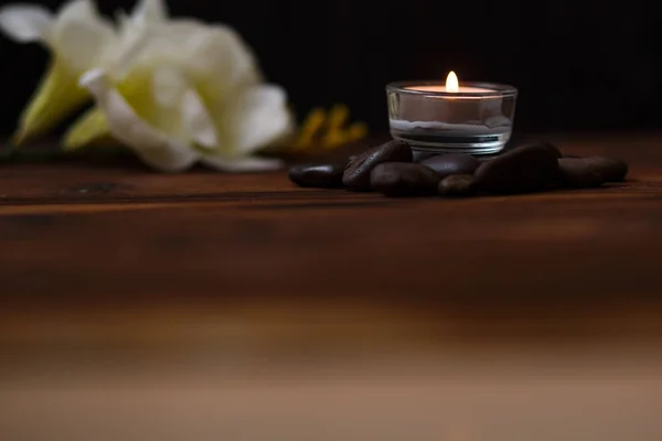 Una vela en un jarrón de vidrio, decoración y varios elementos interesantes sobre un fondo de madera oscura. Velas encendidas. Set para spa y masaje . — Foto de Stock