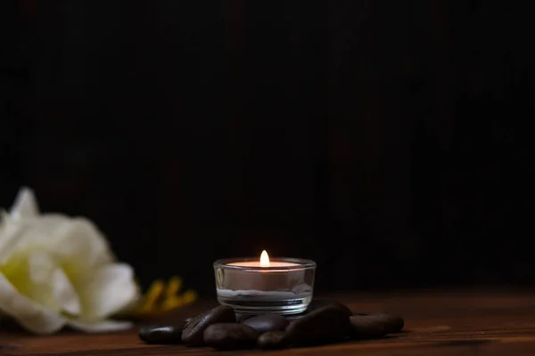 Una vela en un jarrón de vidrio, decoración y varios elementos interesantes sobre un fondo de madera oscura. Velas encendidas. Set para spa y masaje . Imagen De Stock