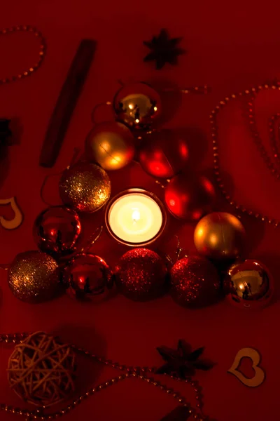 Gouden en rode ballen op de rode achtergrond. Kaarsen in decoraties. — Stockfoto
