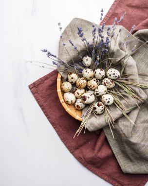 Bir tabakta bıldırcın yumurtaları mermer bir masanın üstünde, üstü örtülü, üst manzara.