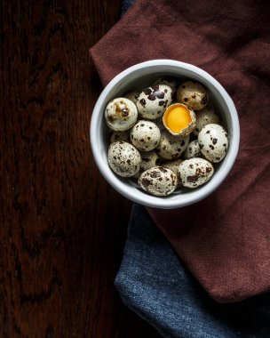 Bir tabakta bıldırcın yumurtası, ahşap bir masanın üstünde, üstü örtülü, üst görünüm.