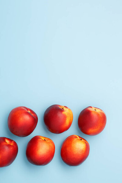 A few ripe red nectarines on a blue background