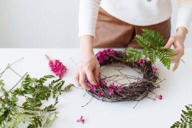 Çiçekçi kız, beyaz bir masada yuva şeklinde bir buket yapar.