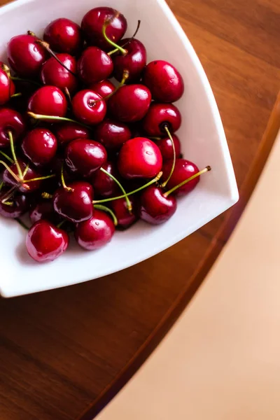 Cerezas Una Placa Cuadrada Blanca Sobre Mesa Madera Marrón — Foto de Stock