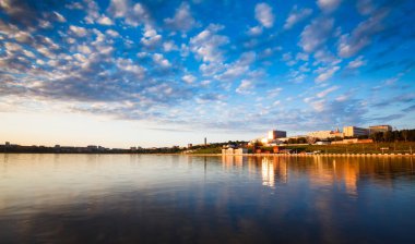 Şehir göletinin üzerinde gün batımı. Bulutlu gökyüzü