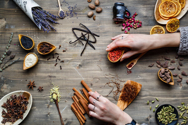 Different spices, herbs and roots view from the top. On rustic background. woman hands put some of them