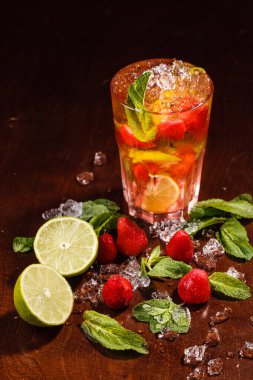 Çiğ meyve ve limonla dolu bir bardaktaki horoz kuyruğu ve kırılmış buz ve nane.