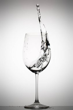 Arkaplanda şarap bardağına su sıçrıyor.