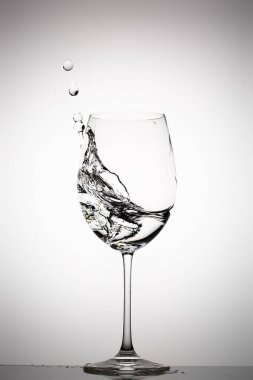 Arkaplanda şarap bardağına su sıçrıyor.