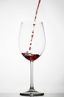 Kırmızı şarap beyaz arka planda bir bardağa sıçrar.