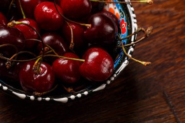 Siyah arka planda mavi bir kasede vişne.