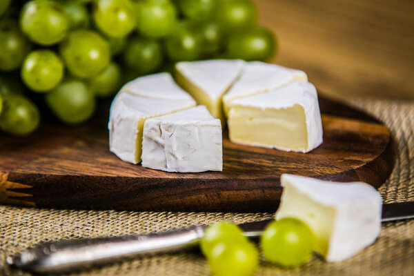 cheese with white grape on a wooden board