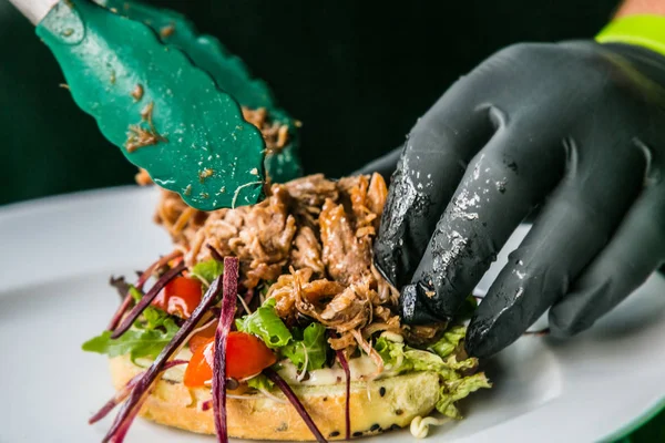 Şefin taze burger hazırlarken ellerini kapat. Yemek pişirme konsepti 