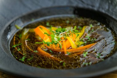 Siyah tabakta servis edilen lezzetli sebze çorbası.