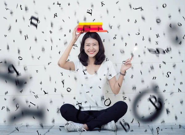 Asian lady sitting with a book and rain of alphabet — Stock Photo, Image