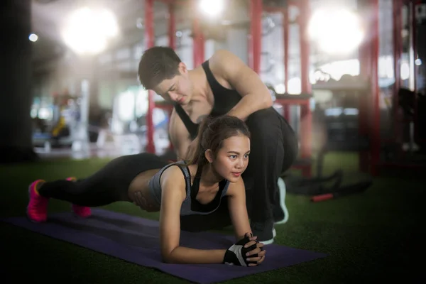 Entraîneur asiatique et dame prendre un entraînement personnel dans le club de fitness — Photo