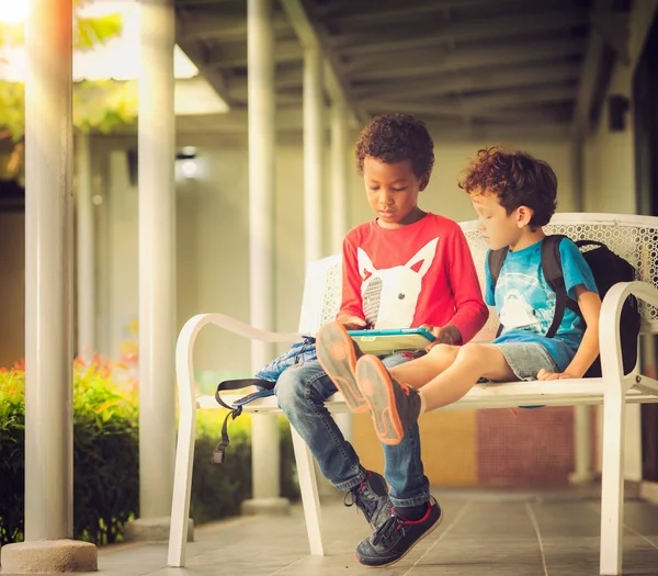 Anerican boy hrát hru v tabletu togather v parku — Stock fotografie