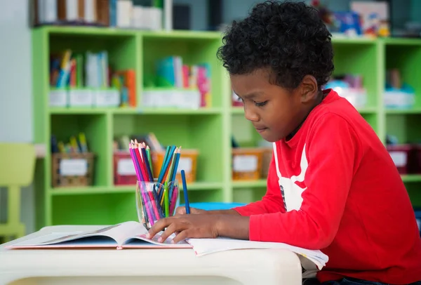 Menino americano fazer casa usava e desenho na biblioteca pré-escolar — Fotografia de Stock